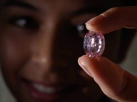 In this file photo taken on November 06, 2020, a model poses with the “The Spirit of the Rose” a rare 14,83 carats vivid purple pink diamond, during a press preview ahead of sales by Sotheby's auction house, in Geneva. The rare pink diamond derived from the biggest raw stone of the colour ever found in Russia was sold for 26,6 million USD on November 11, 2020, at Sotheby's in Geneva. AFP
