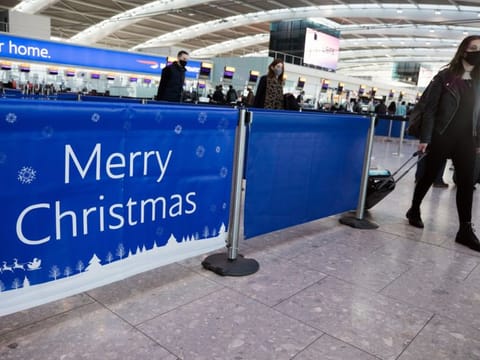 A passenger passes a 'Merry Christmas' sign in the check-in area in at London Heathrow.