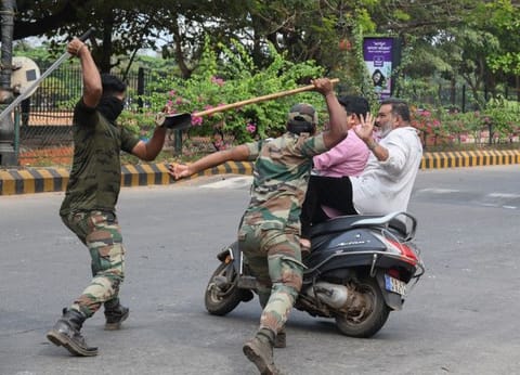 In this file picture taken on December 20, members of the Karnataka Reserve Police Force swing their sticks locally known as 'lathi' to beat two men on a scooter who rode too close to a barricade set up on a street in Mangalore.