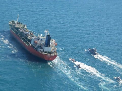 A seized South Korean-flagged tanker is escorted by Iranian Revolutionary Guard boats in the Arabian Gulf.