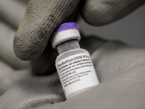 A pharmacist holding with gloved hands a phial of the undiluted Pfizer-BioNTech vaccine for COVID-19, stored at -70 ° in a super freezer.