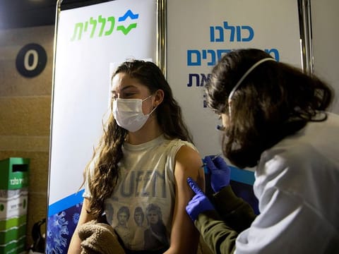 A young woman receives a vaccination against the COVID-19 at a temporary Clalit healthcare maintenance organisation (HMO) centre, at a sports arena in Jerusalem.