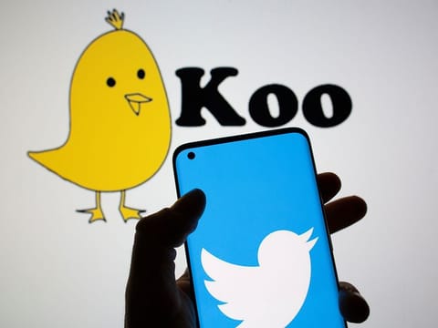 Twitter logo is seen on smartphone in front of displayed Koo app logo in this illustration.