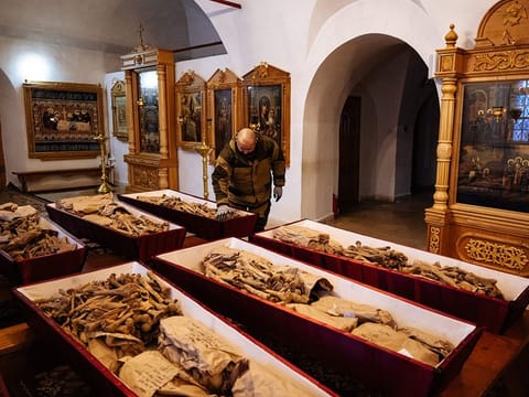 A municipal employee arranges coffins containing remains of Russian and French soldiers who died during Napoleon's 1812 retreat, in a small church in the monastery of John the Precursor in the town of Vyazma.