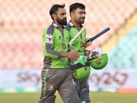 Rashid Khan (right) and Mohammed Hafeez walk back after taking Lahore Qalandars over the line against Peshawar Zalmi on Sunday.