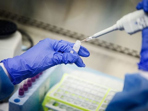 In this March 11, 2020 photo, a laboratory technician prepares COVID-19 patient samples for semi-automatic testing at Northwell Health Labs, in Lake Success, New York.