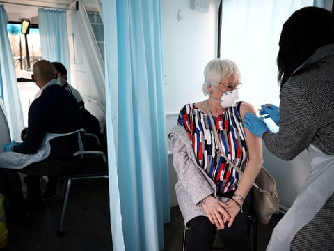 A woman receives a dose of the Oxford-AstraZeneca COVID-19 vaccine inside a bus modified into a mobile vaccination centre for the coronavirus disease (COVID-19), in Thamesmead, London, Britain.