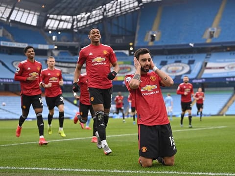 Manchester United's Portuguese midfielder Bruno Fernandes (R) celebrates with teammates after scoring the opening goal from the penalty spot.