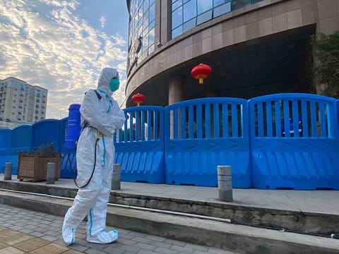 In this file photo dated Saturday, Feb. 6, 2021, a worker in protective overalls and carrying disinfecting equipment walks outside the Wuhan Central Hospital where Li Wenliang, the whistleblower doctor who sounded the alarm and was reprimanded by local police for it in the early days of Wuhan's pandemic, worked in Wuhan in central China.