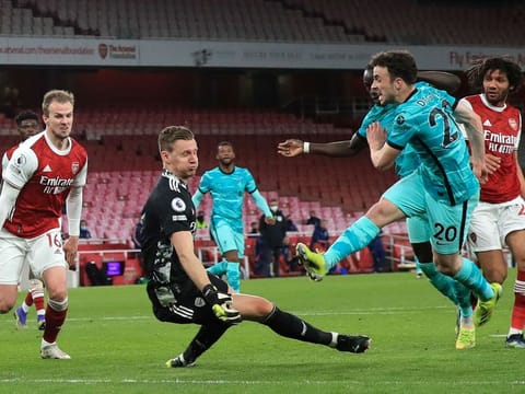 Liverpool's Diogo Jota, right, scores his sides third goal past Arsenal's goalkeeper Bernd Leno