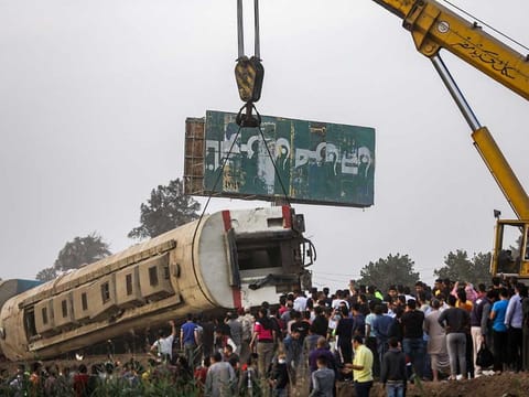 A crane lifts an overturned passenger carriage after a railway accident in the city of Toukh in Egypt's central Nile Delta province of Qalyubiya on April 18, 2021.