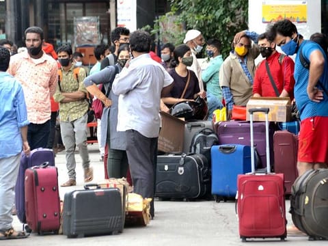 People wait to board buses heading back home after the Karnataka government announced a 14-day shutdown, at Jalahalli bus stand in Bengaluru on Monday, April 26, 2021.