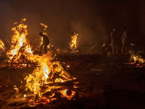 People cremate the bodies of victims of the coronavirus disease (COVID-19), at a crematorium ground in New Delhi.