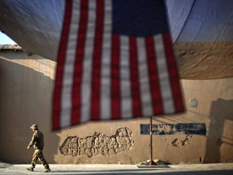 In this September 11, 2011 file photo, a US Army soldier walks past an American flag hanging in preparation for a ceremony commemorating the tenth anniversary of the 9/11 attacks, at Forward Operating Base Bostick in Kunar province, Afghanistan. The final phase of ending America's “forever war” in Afghanistan after 20 years formally began Saturday, May 1, 2021, with the withdrawal of the last US and NATO troops by the end of summer.