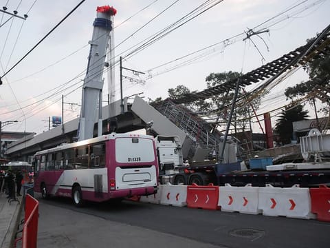A public bus passes along the street after workers moved two train cars at the accident site, where an overpass of the metro partially collapsed with train cars on it, in Mexico City, Mexico May 4, 2021.