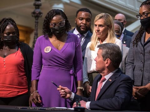 Georgia Gov. Brian Kemp hands a pen to Wanda Cooper-Jones, the mother of Ahmaud Arbery, on Monday, May 10, 2021 at the state capitol in Atlanta. Kemp signed a law repealing citizen's arrest in Georgia, partly blamed for Ahmaud Arbery's fatal shooting death near Brunswick in 2020.