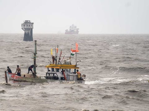 Fishermen on a boat try to recover their smaller boat which had drifted away due to rough sea owing to Cyclone Tauktae, in Mumbai, Tuesday, May 18, 2021.