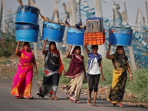 Women carry their belongings after salvaging them from their damaged workplaces at a fishing harbour following Cyclone Tauktae in Jafrabad in the western state of Gujarat, India, May 19, 2021.