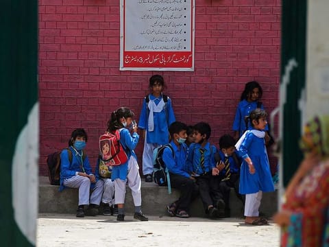 Students wait under a shade for transport at a school on a hot summer day in Rawalpindi on June 10, 2021.