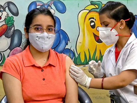 A health worker inoculates a woman with a jab of Covishield's COVID-19 vaccine at a vaccination Centre in New Delhi on June 21, 2021 after India opened up free vaccinations to all adults in an attempt to bolster its inoculation drive.