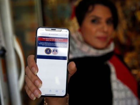 An Iranian woman shows on her mobile phone a statement declaring the website of Iran's English-language television station Press TV "has been seized by the United Government", in the capital Tehran on June 23, 2021.