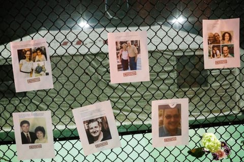 Pictures of missing people and flowers hang on a fence at the memorial for victims of a partially collapsed residential building as the emergency crews continue search and rescue operations for survivors, in Surfside, near Miami Beach, Florida, US June 25, 2021.
