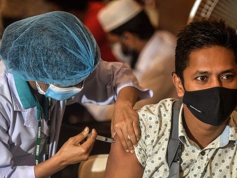 A health worker inoculates a man with a dose of the Oxford-AstraZeneca Covid-19 vaccine at the Bangabandhu Sheikh Mujib Medical University Hospital (BSMMU), in Dhaka on June 22, 2021.