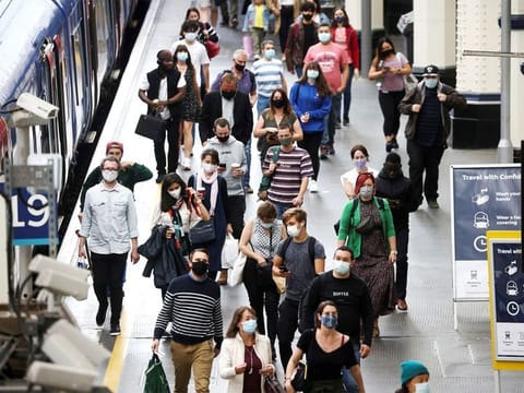 People, some wearing protective face masks, walk through Waterloo Station, in London, on July 4, 2021.