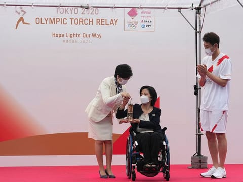 Tokyo Governor Yuriko Koike, left, receives a lantern containing the Olympic Flame from Aki Taguchi, centre, official ambassador of the Tokyo 2020 Torch Relay, as former tennis player Shuzo Matsuoka, right, applauds during the unveiling ceremony for Olympic Flame of the Tokyo 2020 Olympic torch relay at Komazawa Olympic Park, Friday, July 9, 2021, in Tokyo.