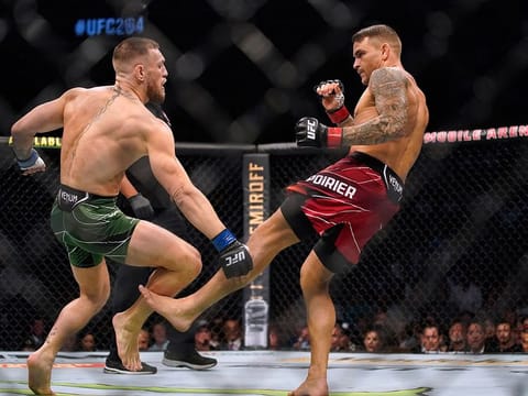 Dustin Poirier, right, kicks Conor McGregor during UFC 264