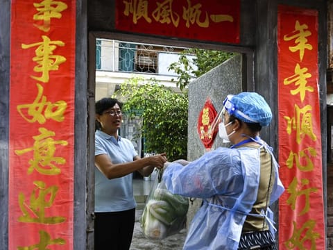 In this photo released by Xinhua News Agency, a community worker delivers daily necessities to a household under closed-off management in the city of Ruili in southwestern China's Yunnan Province on July 8, 2021. Chinese authorities locked down the city bordering Myanmar on Wednesday, shutting most businesses and requiring residents to stay at home as a fresh outbreak of COVID-19 expanded.