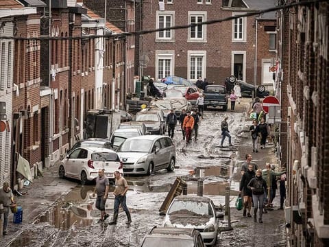 People walk through a damaged street after flooding in Chenee, Province of Liege, Belgium. Severe flooding in Germany and Belgium has turned streams and streets into raging torrents that have swept away cars and caused houses to collapse.