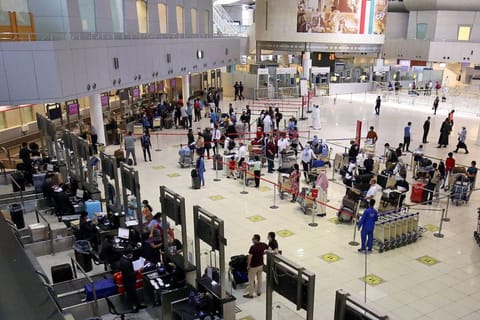 Passengers queue at the check-in counters prior to their departure at Kuwait International Airport in Kuwait City on July 15, 2021.