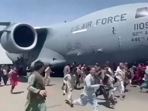 Hundreds of people run alongside a US Air Force C-17 transport plane as it moves down a runway of the international airport, in Kabul, Afghanistan, Monday, Aug. 16. 2021.