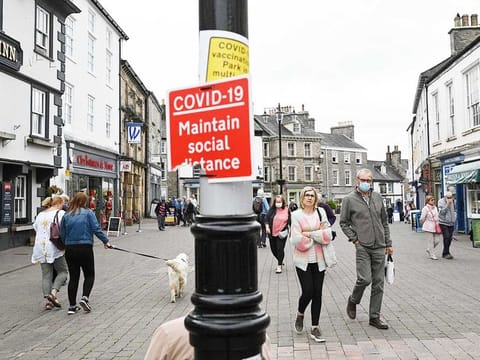 In this file photo taken on June 21, 2021 Members of the public, some wearing face coverings due to COVID-19, walk past shops in Kendal in Cumbria, north west England on June 21, 2021, where surge testing has been deployed following an outbreak of a coronavirus variant of concern.