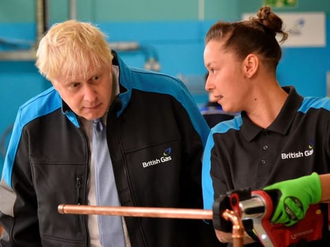 Britain's Prime Minister Boris Johnson listens to apprentice Amy Gray during a visit to a British Gas training academy near Leicester, central England on September 13, 2021. Expanded vaccinations are expected to be part of a “tool kit’’ to control COVID-19 infections this fall and winter that Prime Minister Boris Johnson plans to announce on Tuesday at a news conference.