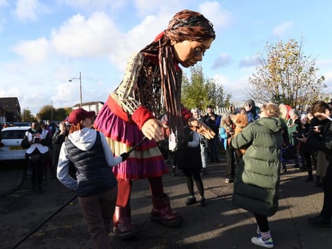 Little Amal, a 3.5 metre tall 10 year-old Syrian refugee puppet meets well-wishers in Govan, Glasgow on November 10, 2021, during the COP26 UN Climate Change Conference.