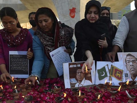 Members of the Human Rights Council of Pakistan place oil lamps to pay tribute beside a photograph of late Sri Lankan factory manager Priyantha Kumara, in Karachi on December 5, 2021, after he was beaten to death and set ablaze by a mob who accused him of blasphemy.