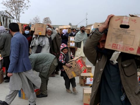 Afghans carrying packages distributed by a Turkish humanitarian aid group, leave a distribution centre in Kabul, Afghanistan.