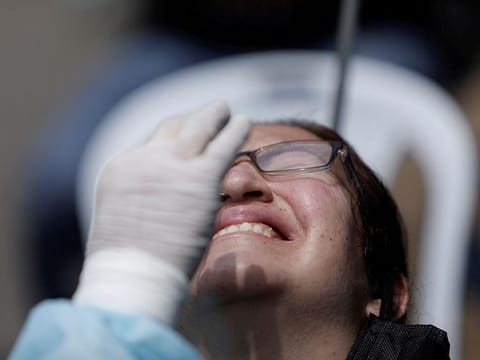 A person reacts as they get tested for COVID-19 as Peru raised its pandemic alert level in various cities due to a third wave of infections caused by Omicron variant, in Lima, on January 6, 2022.