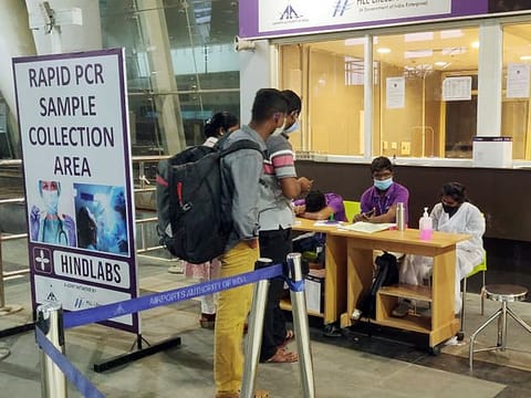 Passengers wait at a rapid PCR sample collection area, at Chennai International Airport, in Chennai