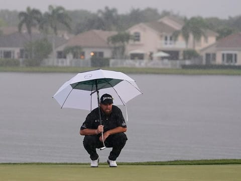 Shane Lowry looks at his shot as heavy rain falls on the 18 green during the final round of the Honda Classic