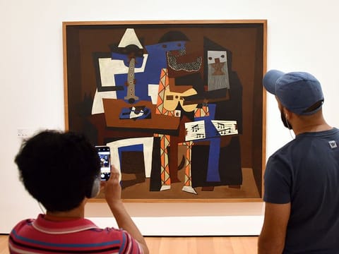 Visitors near the Pablo Picasso Three Musicians painting in Museum of Modern Art in New York City