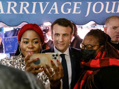 French President and liberal party La Republique en Marche (LREM) candidate for re-election Emmanuel Macron poses for a picture as he meets people at an open market in Neuilly-sur-Seine, near Paris, on April 8, 2022, on his way out of an interview at French private radio station RTL, two days before the first round of the French presidential election.
