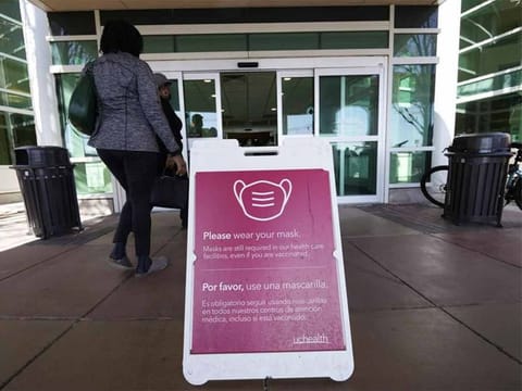 A sign advising visitors to don face coverings stands outside the main entrance to UCHealth University of Colorado hospital, in Aurora. COVID cases are starting to rise again in US, with numbers up in most states and up steeply in several.