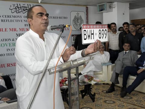 Sindh Excise and Taxation Minister, Mukesh Kumar Chawla, displays a new vehicle registration plate.