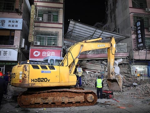 Rescuers work next to an excavator at a site where a building collapsed in Changsha, Hunan province, China.