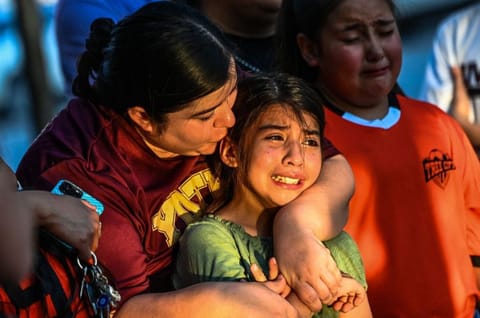 Gabriella Uriegas, a soccer teammate of Tess Mata who died in the shooting, cries while holding her mother Geneva Uriegas as they visit a makeshift memorial outside the Uvalde County Courthouse in Texas on May 26, 2022.