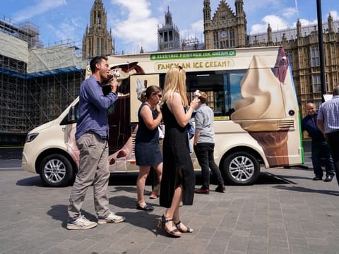 People eat ice cream outside the houses of Parliament, in London.