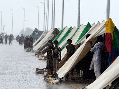File picture: People who fled their flood hit homes stand outside temporary tents set along a road during a heavy monsoon rainfall in Sukkur of Sindh province.